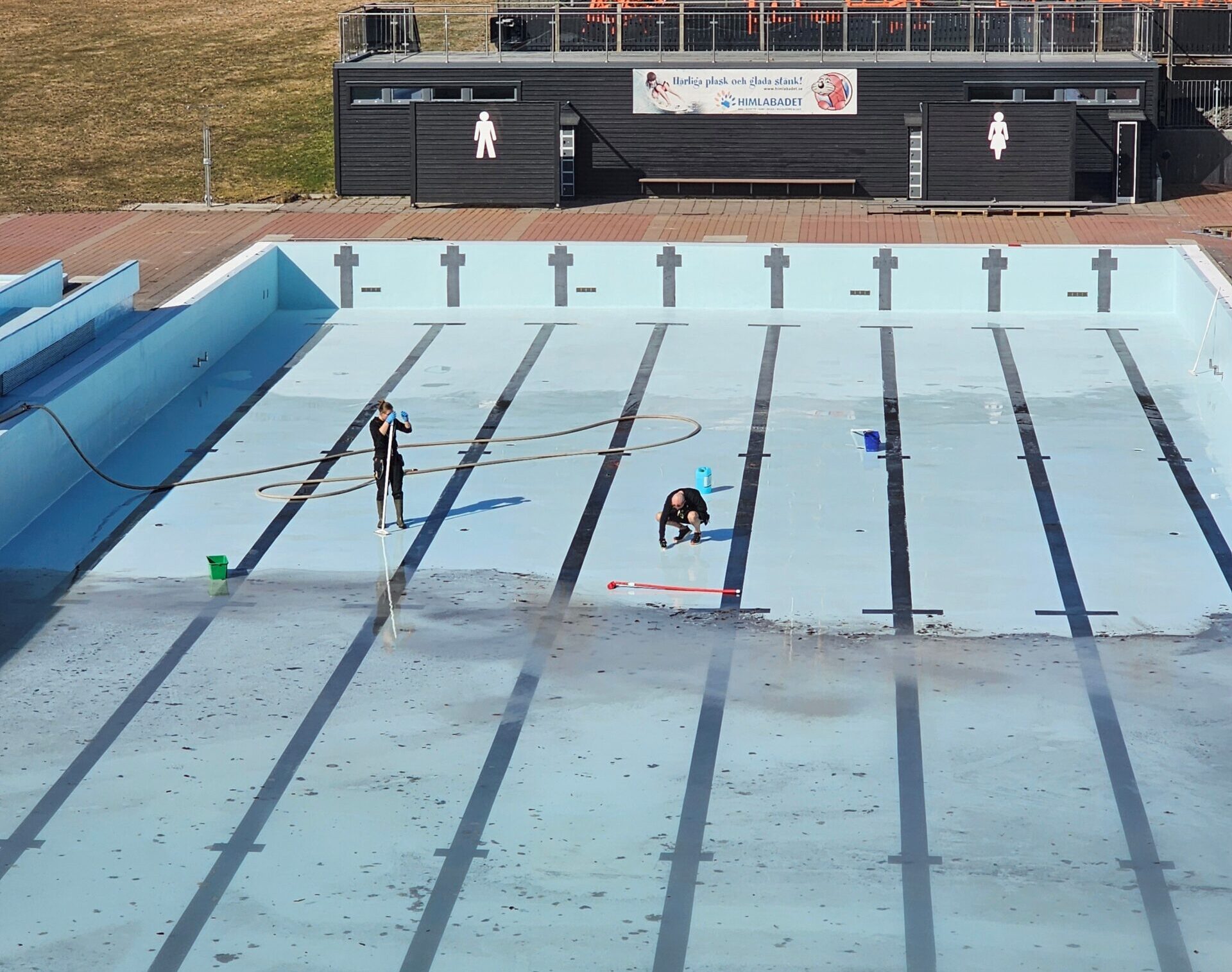 Två tekniker städar bassängen